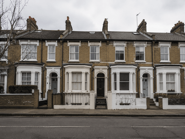 A row of yellow stock brick Victorian terraces seen from across the road, bay windows and painted stucco porches