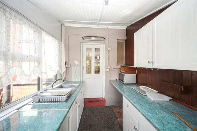 The galley kitchen of an unmodernised inherited house, dated but sound